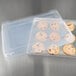 A plastic container with a Vollrath bun pan cover on it filled with cookies.