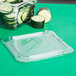 A Carlisle clear plastic container lid with cucumber slices inside.
