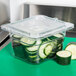 A Carlisle 1/6 size clear plastic lid on a container of cucumber slices.