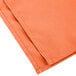 An orange Intedge cloth napkin folded up.