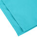 A folded teal Intedge cloth napkin.