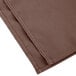 A brown Intedge cloth napkin with white stitching.
