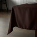 A brown Intedge square table cloth on a table.