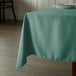 A table with a seafoam green Intedge square tablecloth on it.