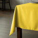 A table with a yellow Intedge rectangular tablecloth on it.