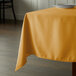 A square gold Intedge table cover on a table in a restaurant.
