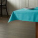 A table with a teal square tablecloth and a plate on it.