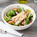 A Tuxton eggshell china bowl filled with salad with chicken, carrots, and lettuce.