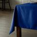 A rectangular royal blue Intedge tablecloth on a wooden table.