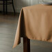 A table with a beige rectangular tablecloth on it.