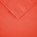 A close-up of an orange rectangular cloth table cover with hemmed edges.