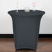 A table with a Snap Drape charcoal spandex table cover and wine glasses on it.
