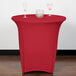 A table with a Snap Drape crimson spandex table cover and two wine glasses on it.