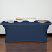 A navy Snap Drape spandex table cover on a table with food in white bowls.