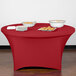 A table with a crimson Snap Drape spandex cover and plates of food on it.