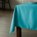 A table with a teal Intedge square table cloth on it.