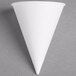 A Bare by Solo white cone shaped paper cup on a gray surface.