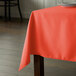 An orange tablecloth on a square table.