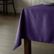 A square purple Intedge table cloth on a table.