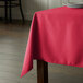 A square table with a hot pink tablecloth on it.