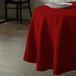 A red Intedge round polyester tablecloth on a table.
