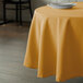 A gold Intedge polyester tablecloth on a table with a white plate.