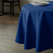 A royal blue Intedge tablecloth on a table with a white plate on it.