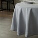 A table with a white Intedge round tablecloth and a plate on it.