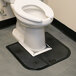 A toilet with a black mat on the floor.