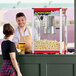 A man and woman at a Carnival King red popcorn machine.