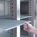 A hand holding an Avantco coated wire shelf