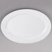 A Tuxton bright white oval china platter on a gray surface.