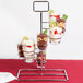 A chrome metal tower dessert shot display stand with three different desserts in glasses.