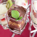 A chrome tower dessert shot display stand holding chocolate desserts in small glasses.