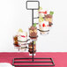 A black tower dessert shot display stand with three different desserts on it.