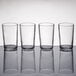 A row of four clear Libbey juice glasses on a table.