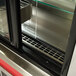 The glass door of a Delfield drop-in refrigerated horizontal air curtain merchandiser on a counter.