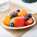 A heart-shaped palm leaf plate with fruit on a table.