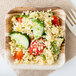 A white square Eco-gecko palm leaf bowl filled with couscous, tomatoes, and cucumbers.
