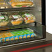 A Delfield countertop glass door refrigerator with a salad and sandwich in plastic containers.