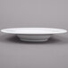 An Arcoroc white porcelain pasta bowl on a gray surface.