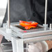 A person uses a Nemco Easy Chopper III to slice a red pepper.