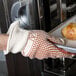 A hand wearing a Cordova hot mill glove holding a tray of bread.