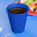 A cobalt blue plastic cup with a drink in it.