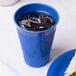 A Creative Converting cobalt blue plastic cup filled with ice next to a sandwich.
