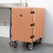 A Cambro beige mobile cart with a single compartment for large plastic food containers on wheels.
