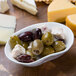 A 10 Strawberry Street bright white porcelain elliptical bowl filled with olives and cheese on a table.