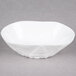 A bright white porcelain small elliptical bowl with a small design on it.