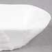 A white porcelain small elliptical bowl with a small white design.