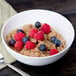 A 10 Strawberry Street white bone china cereal bowl filled with oatmeal and berries with a spoon.